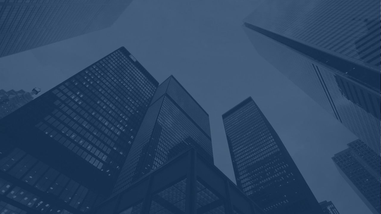 Low-angle view of tall modern glass skyscrapers against a clear sky in a city.