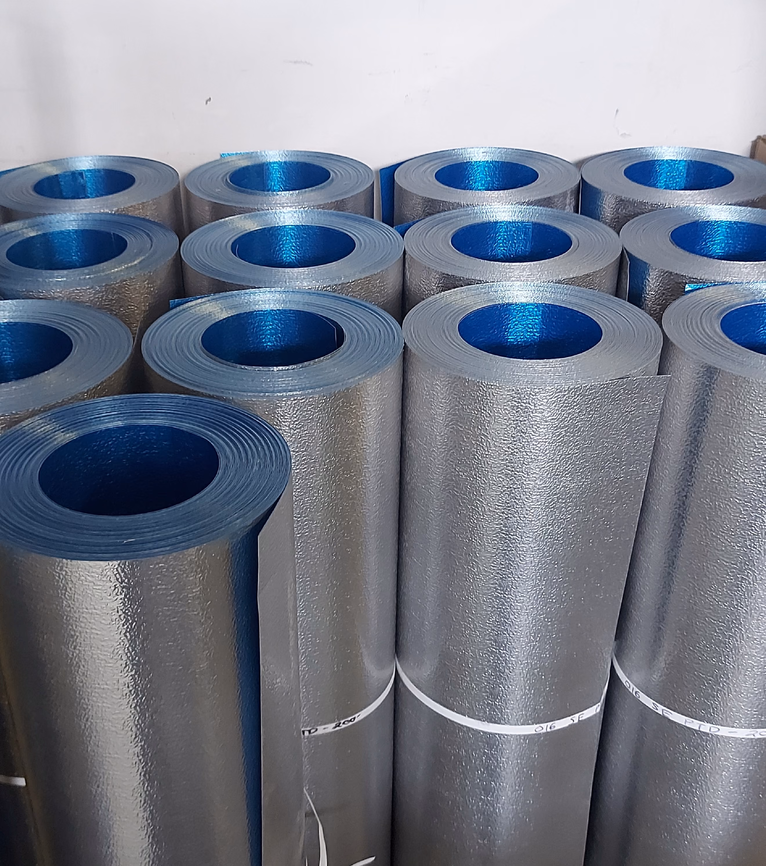 Several shiny insulation foam rolls with blue inner cores standing vertically in rows.