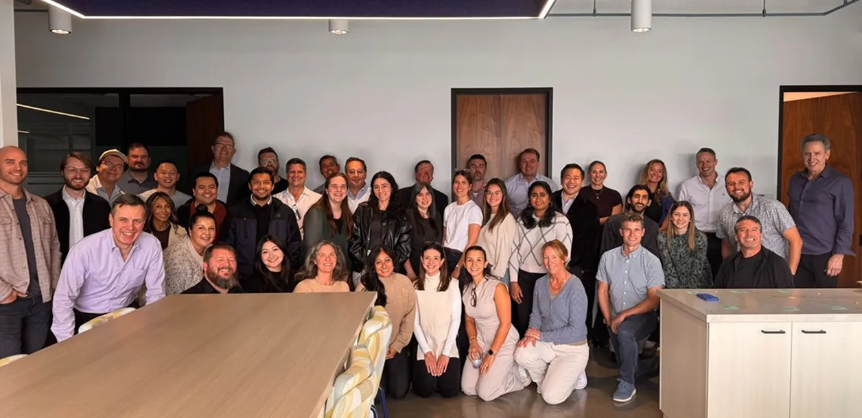 Large group of diverse adults smiling and posing together in an office setting.