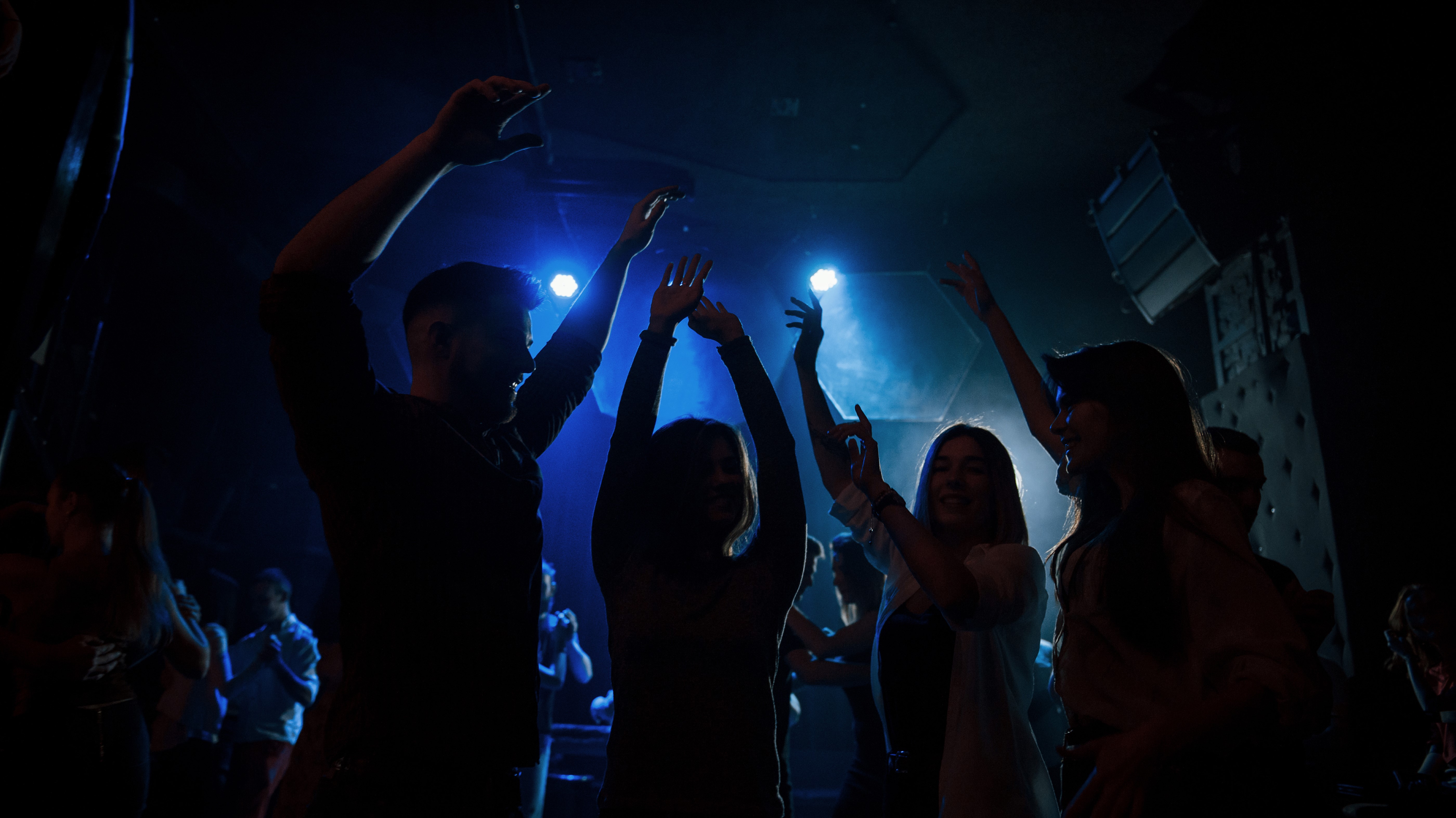 People interacting with colorful, glowing light ribbons in a dark environment, creating abstract neon patterns.