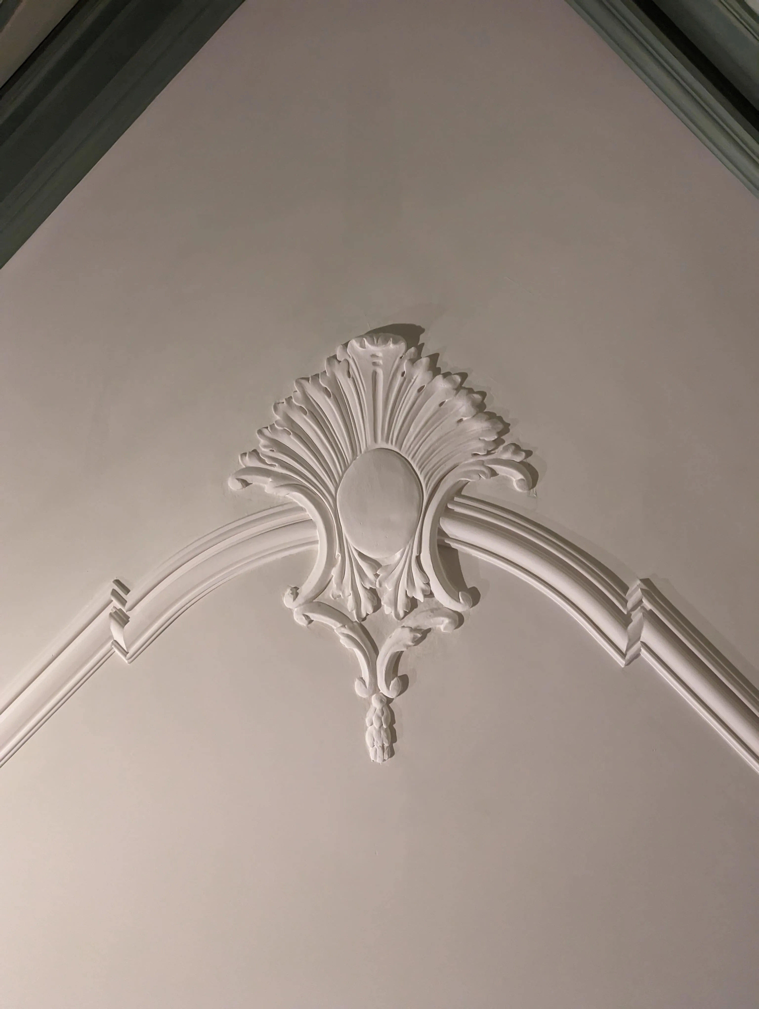 Ornement en plâtre en forme de palmette au sommet d'une arche moulurée