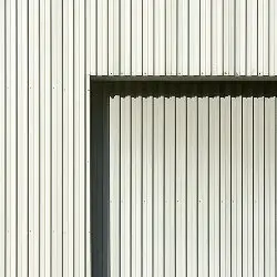 Corrugated metal wall with a rectangular cutout showing aligned panels inside.