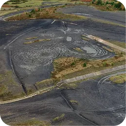 Aerial view of a dried, cracked land area with winding roads and patches of vegetation.