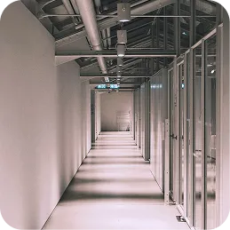 Long corridor with glass doors on the right and exposed ceiling pipes above.