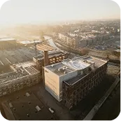 Aerial view of an urban area with a large building and surrounding construction at sunset.