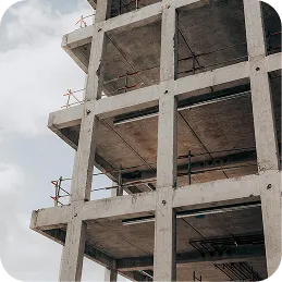 Partially constructed concrete building framework with multiple floors against a cloudy sky.