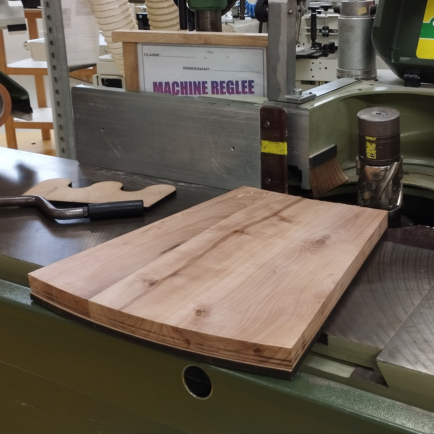 Pièce du tabouret en cormier posée sur une machine