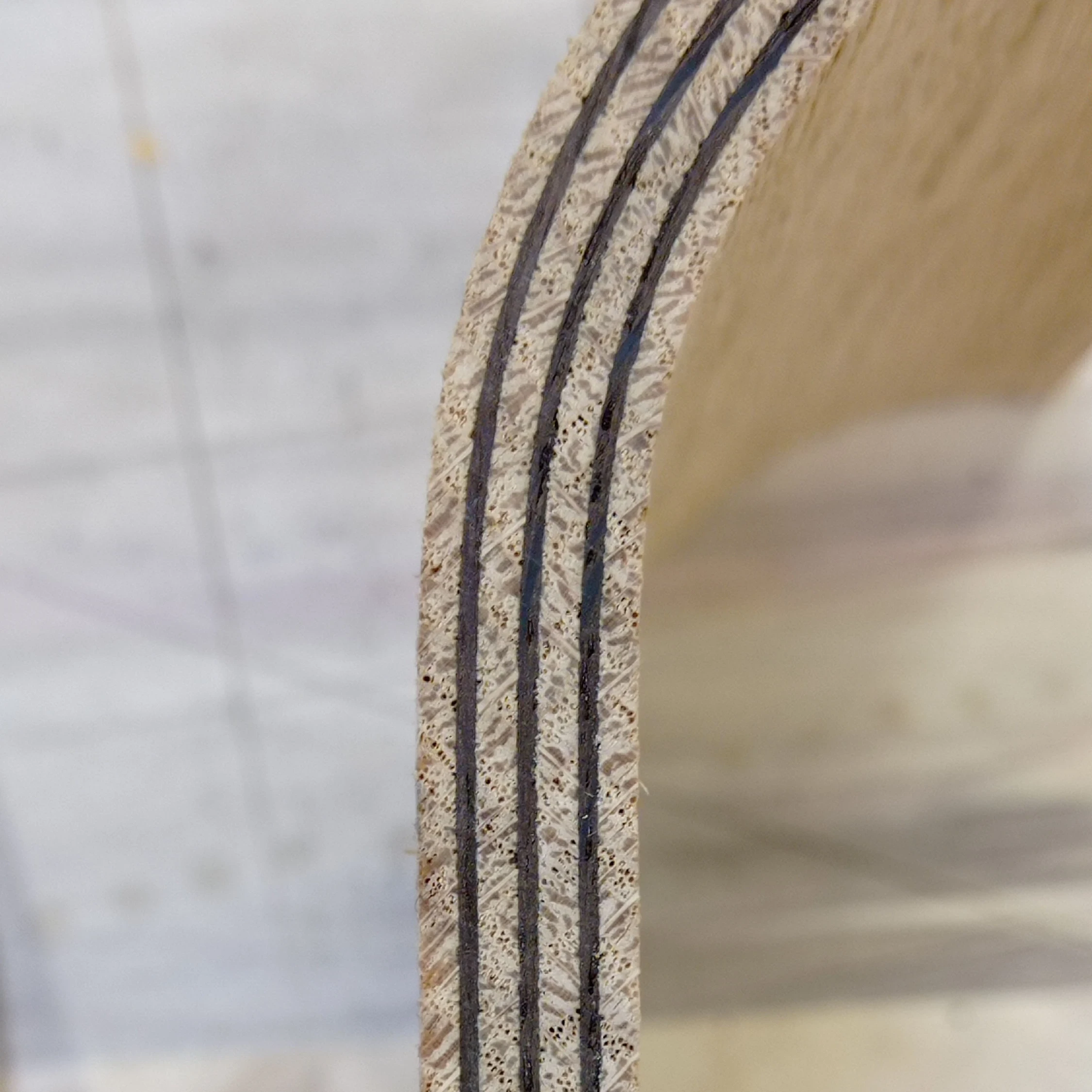 Zoom sur le détail des feuilles de placage alternant entre le chêne naturel et le chêne teinté, formant la coque de l'assise