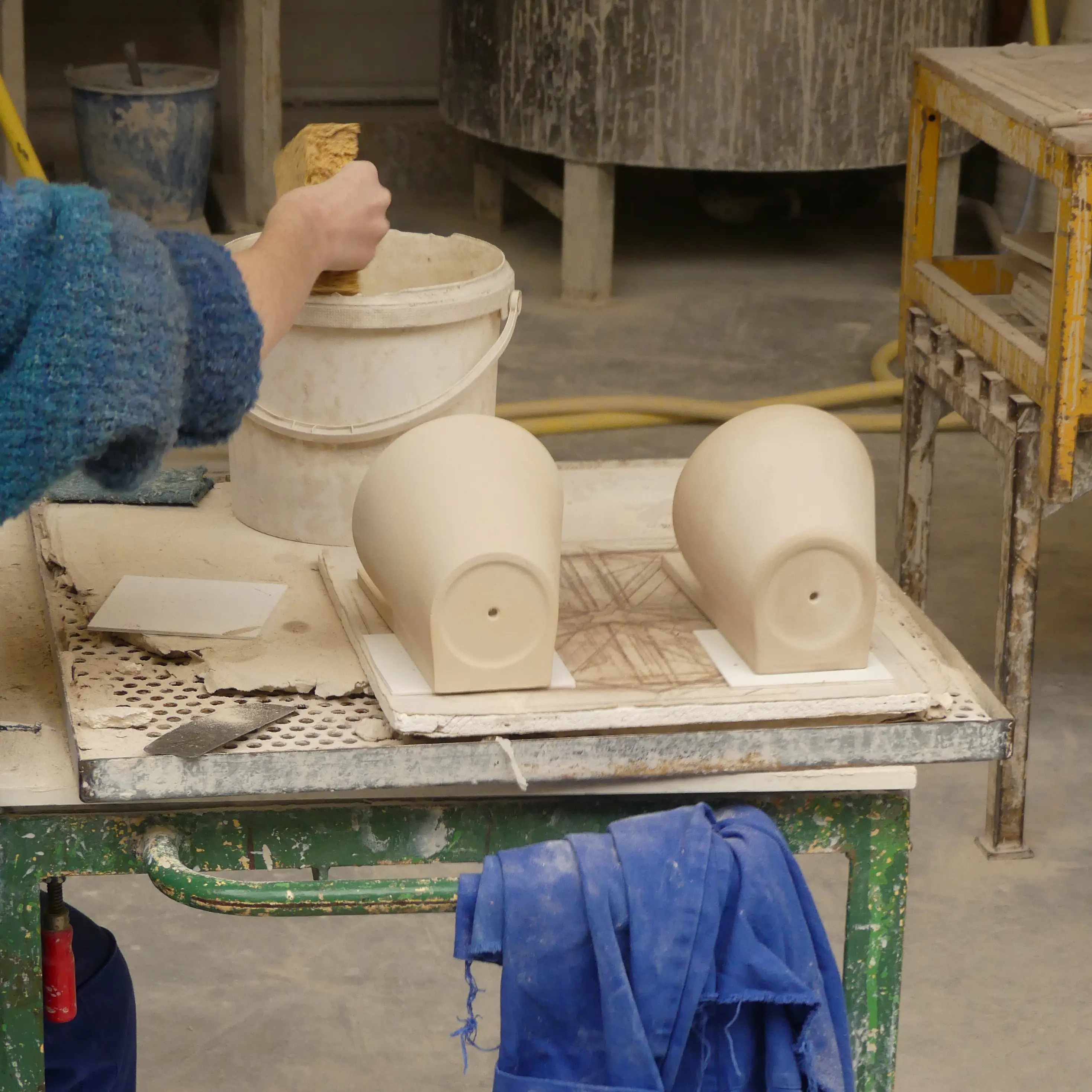 Artisan nettoyant une pièce de céramique dans son altelier