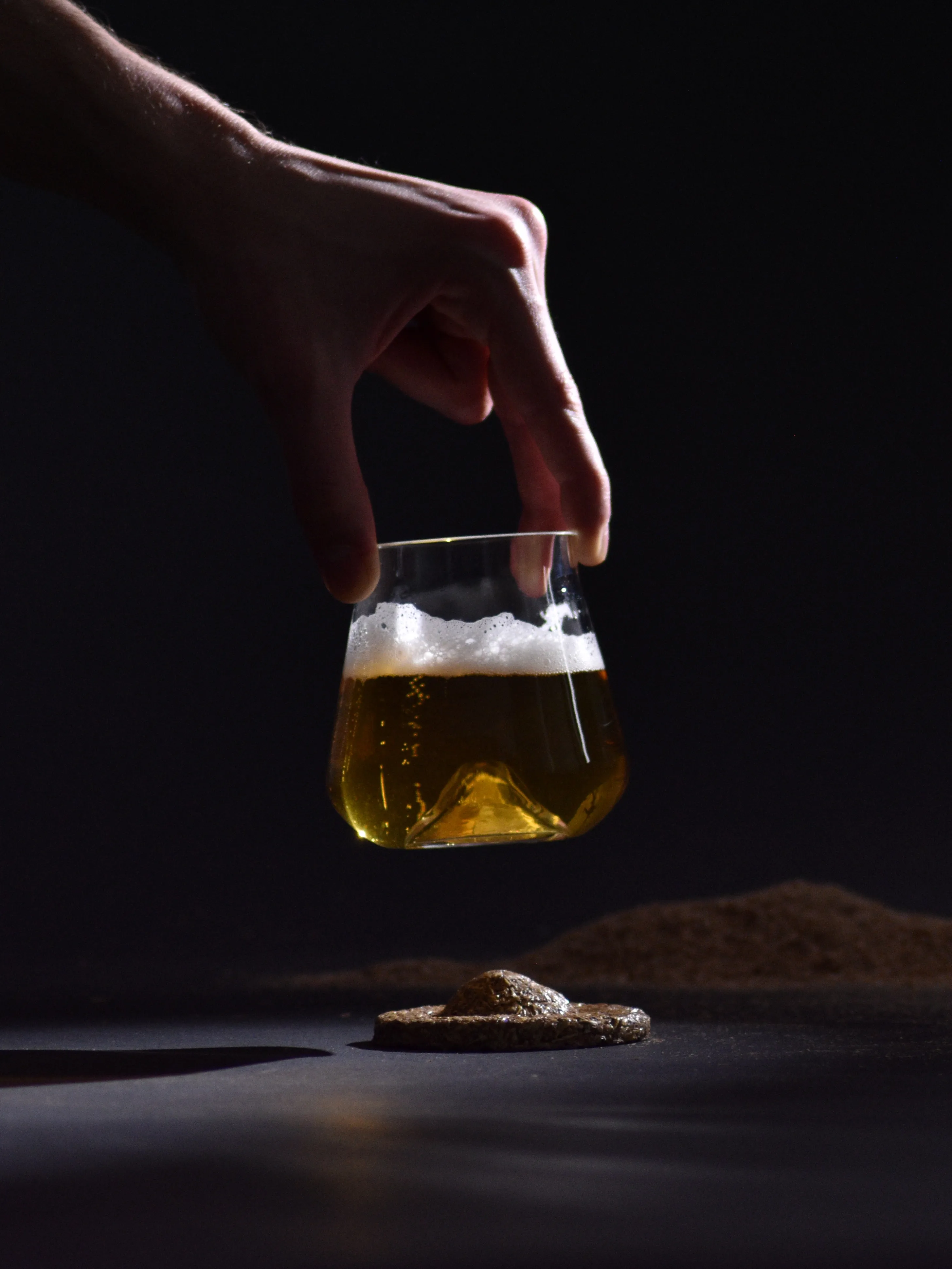 Main tenant le verre rempli de bière sur un fond noir