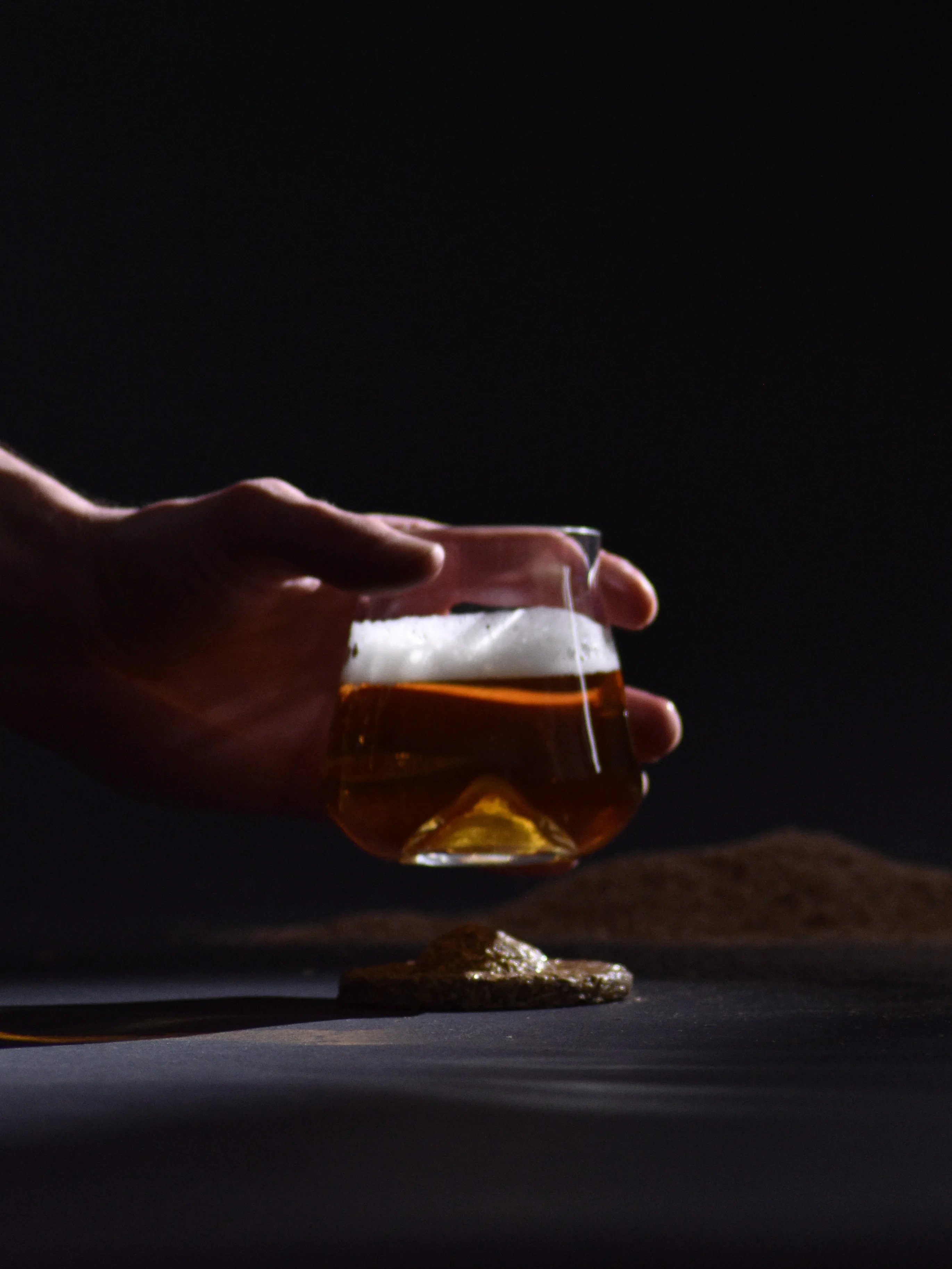Main tenant le verre rempli de bière sur un fond noir