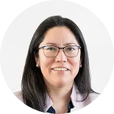 A smiling woman with long, dark hair and glasses against a white background.