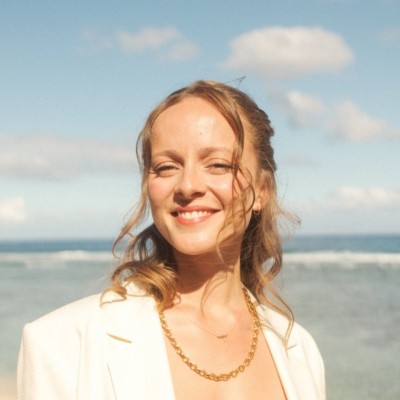 Portrait d'une femme souriante en veste blanche, en bord de mer
