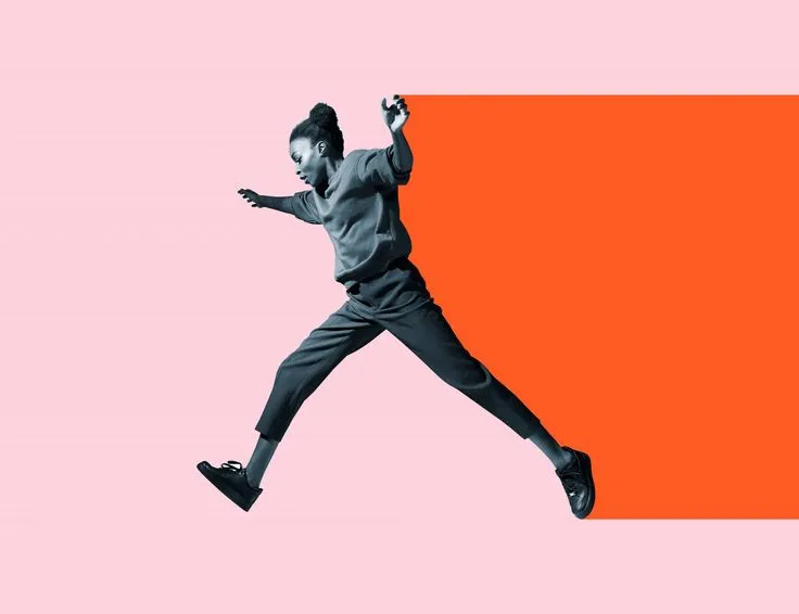 Femme en plein saut devant un aplat orange sur fond rose