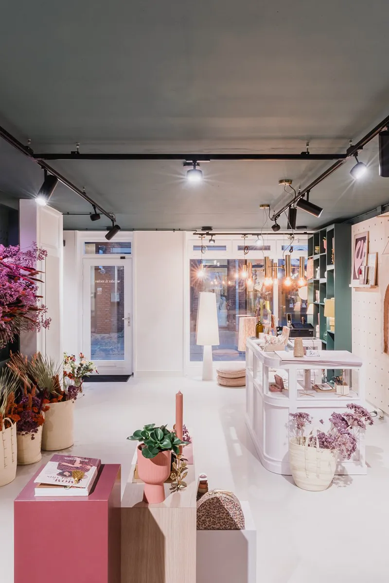 Breed overzicht van lifestyle winkel met zwart railsysteem, meerdere spots en warme hanglampen als compleet retaillichtplan