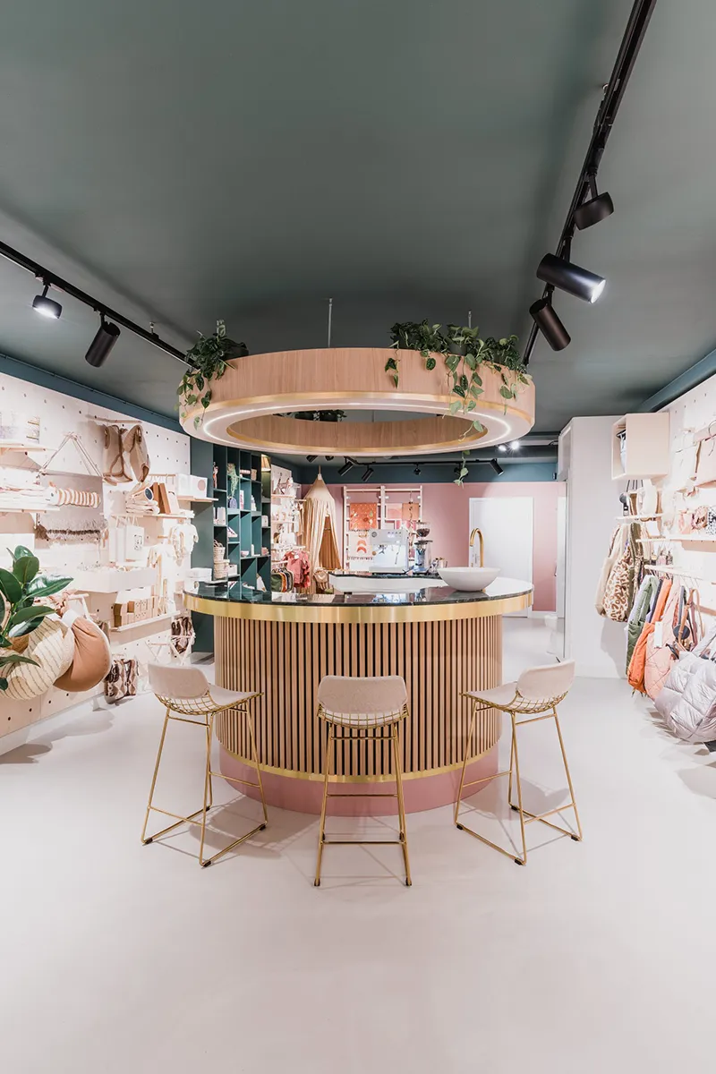 Ronde houten balie met gouden ring en grote verlichte LED-ring aan het plafond in lifestyle winkel met railverlichting