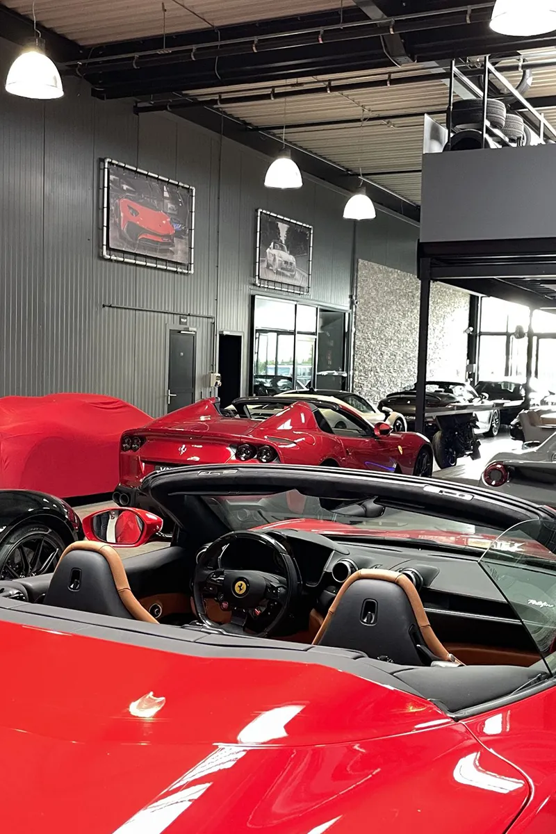 Luxe autogarage met meerdere rode Ferrari's en witte koepelhanglampen als showroomverlichting op maat