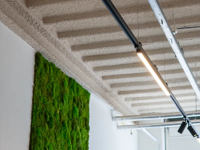 Detailopname van lineaire LED-lamp aan zwart railsysteem naast groene mosswand in modern kantoor