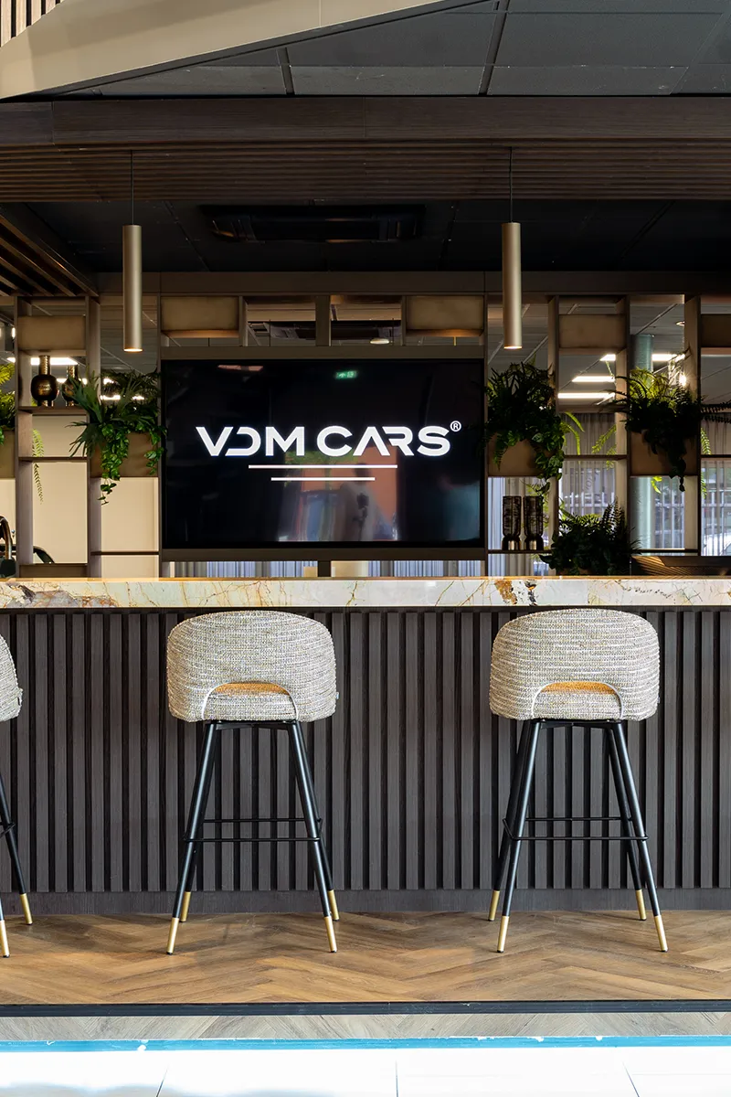 Luxe balie van VDM Cars met marmeren blad, cilindrische hanglampen en groene plantenwand als onderdeel van een zakelijk lichtplan