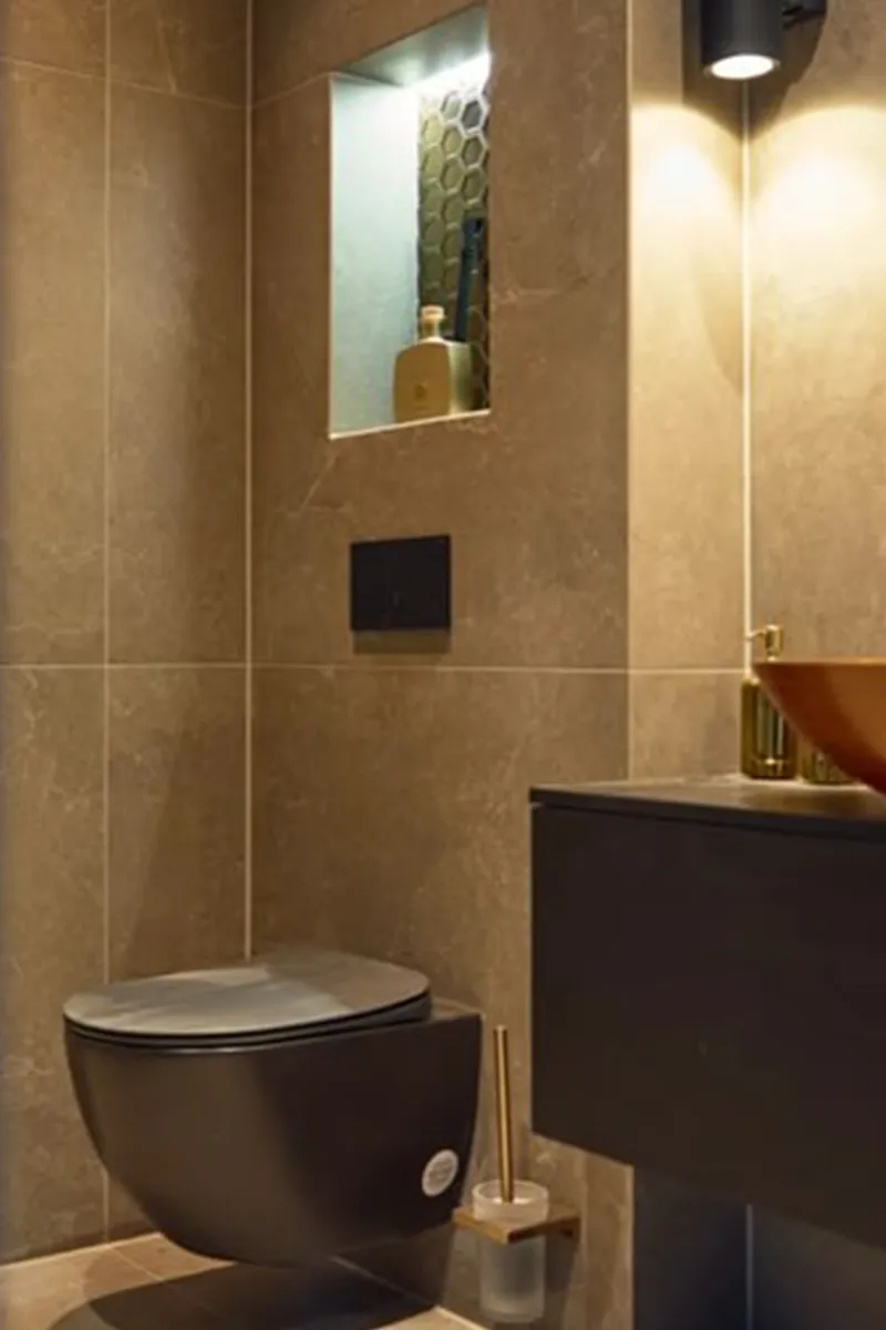 Luxe toiletruimte met gerichte spot, verlichte nis en warme sfeerverlichting op marmerlook tegels