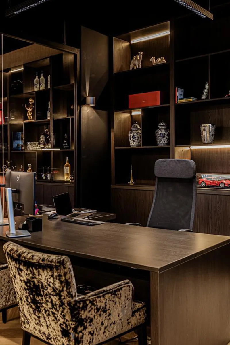 Donker directiekantoor bij House of Capital met indirecte LED-verlichting in wandkasten en sfeervolle wandlamp