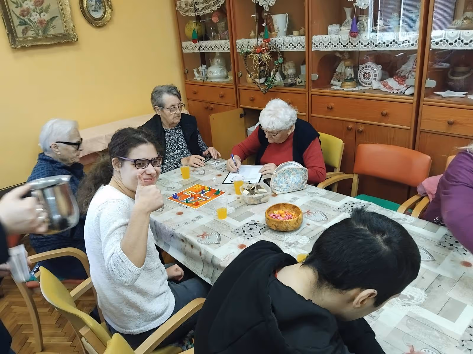 Korisnici i djelatnici Centra igraju društvenu igru Čovječe, ne ljuti se za stolom ukrašenim stolnjakom, uz sok i slatkiše.