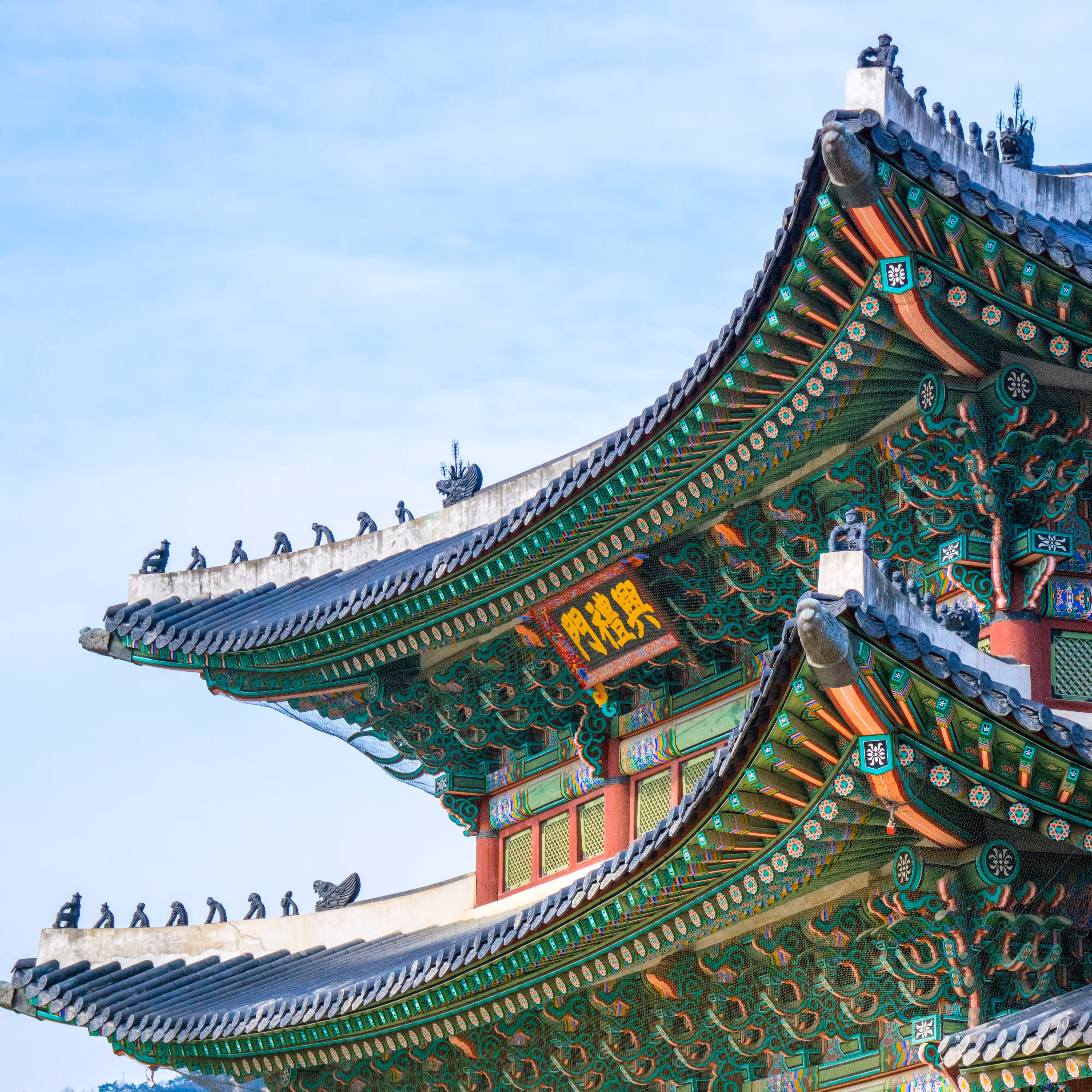 Colorful curved eaves of traditional Korean temple roof with decorative tiles and small statues.
