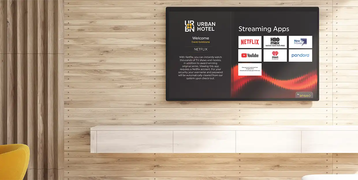 A bright hotel room showcasing the Urban Hotel Streaming Apps page on the TV.