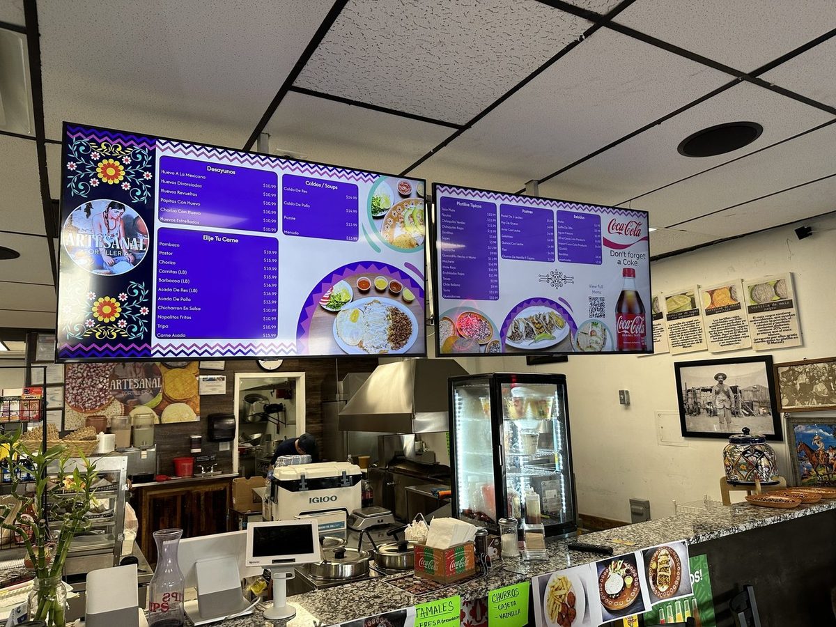 Two purple menu boards with food photos over the counter at Artesanal Tortilleria in San Antonio