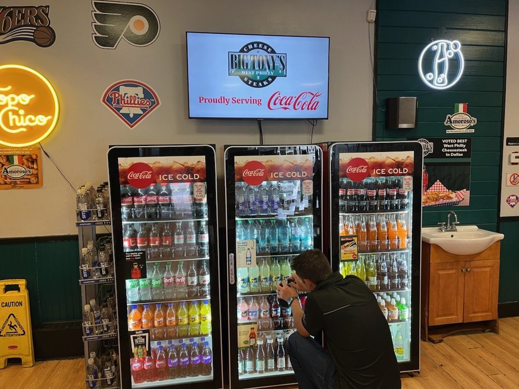 A Just a Menu screen above three Coca-Cola coolers at Big Tony's West Philly Steaks in Dallas