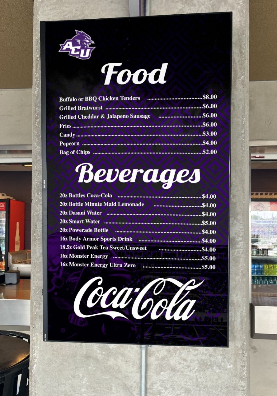 A tall purple Food and Beverages menu screen on a pillar at a university stadium