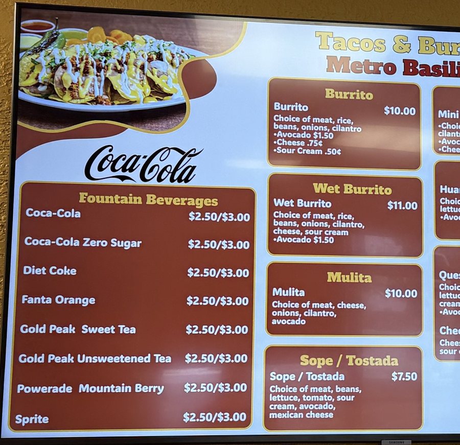 A close-up of the menu board at Tacos & Burritos Metro Basilica 2: fountain drinks, burritos, mulitas and sopes with prices