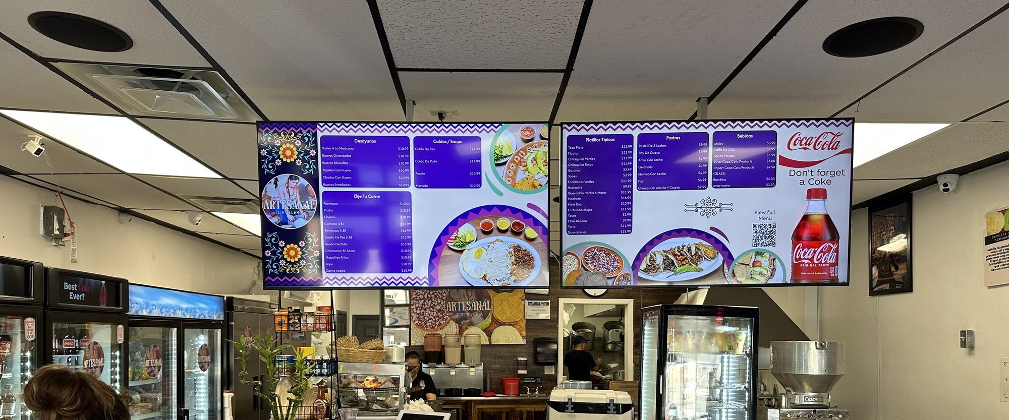 The counter at Artesanal Tortilleria in San Antonio, under two purple menu boards
