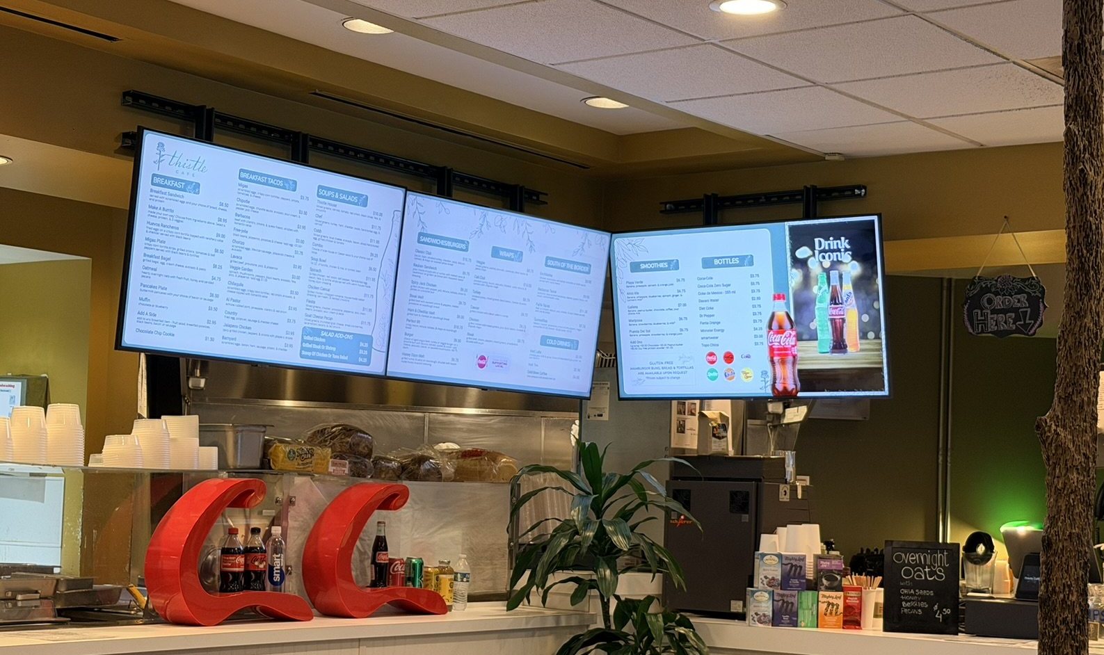 Three Just a Menu boards over the counter at Thistle Cafe in Austin: breakfast, sandwiches and drinks
