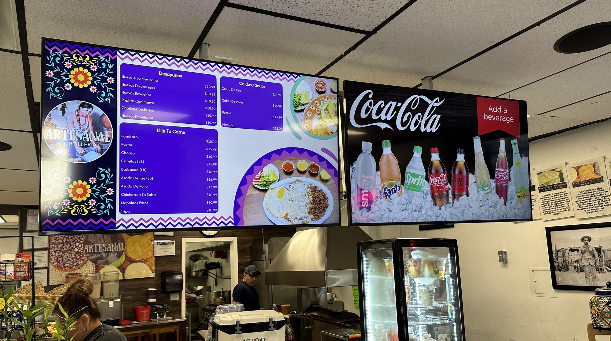 A menu board beside a Coca-Cola drinks board at Artesanal Tortilleria in San Antonio