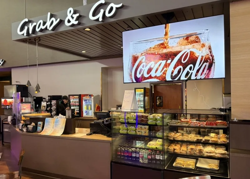 A full-screen Coca-Cola promotion on a menu screen over a casino grab and go