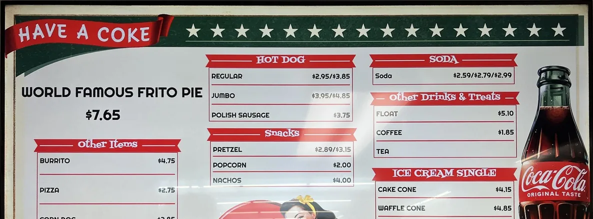 A retro Have a Coke concession menu board with world famous Frito pie, hot dogs, snacks and soda