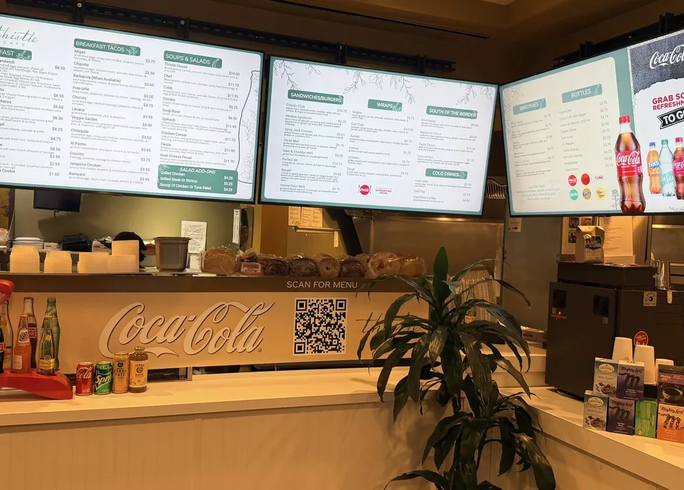 The counter at Thistle Cafe in Austin, with three menu boards above it and a Scan for menu QR code on the front