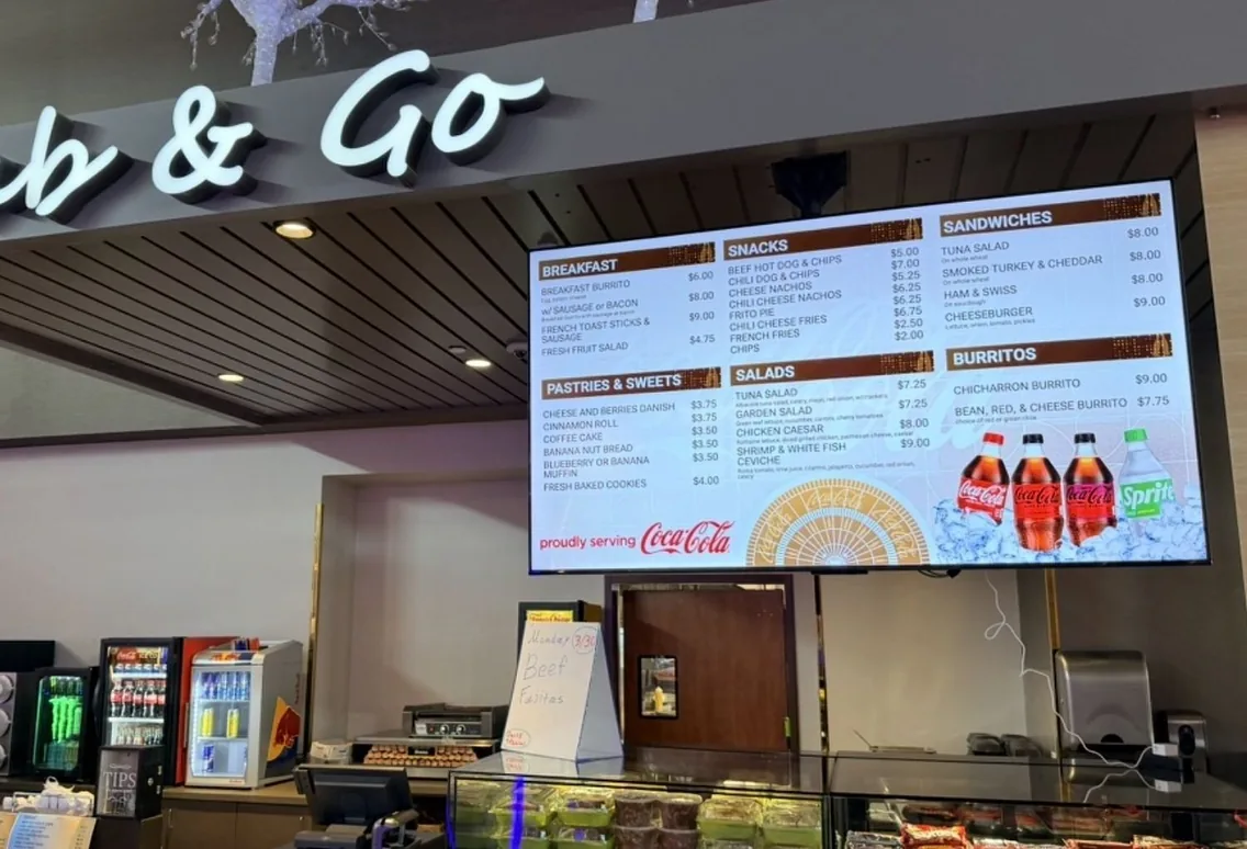 After: a wide digital menu board with breakfast, snacks, sandwiches, salads and burritos over a casino grab and go counter