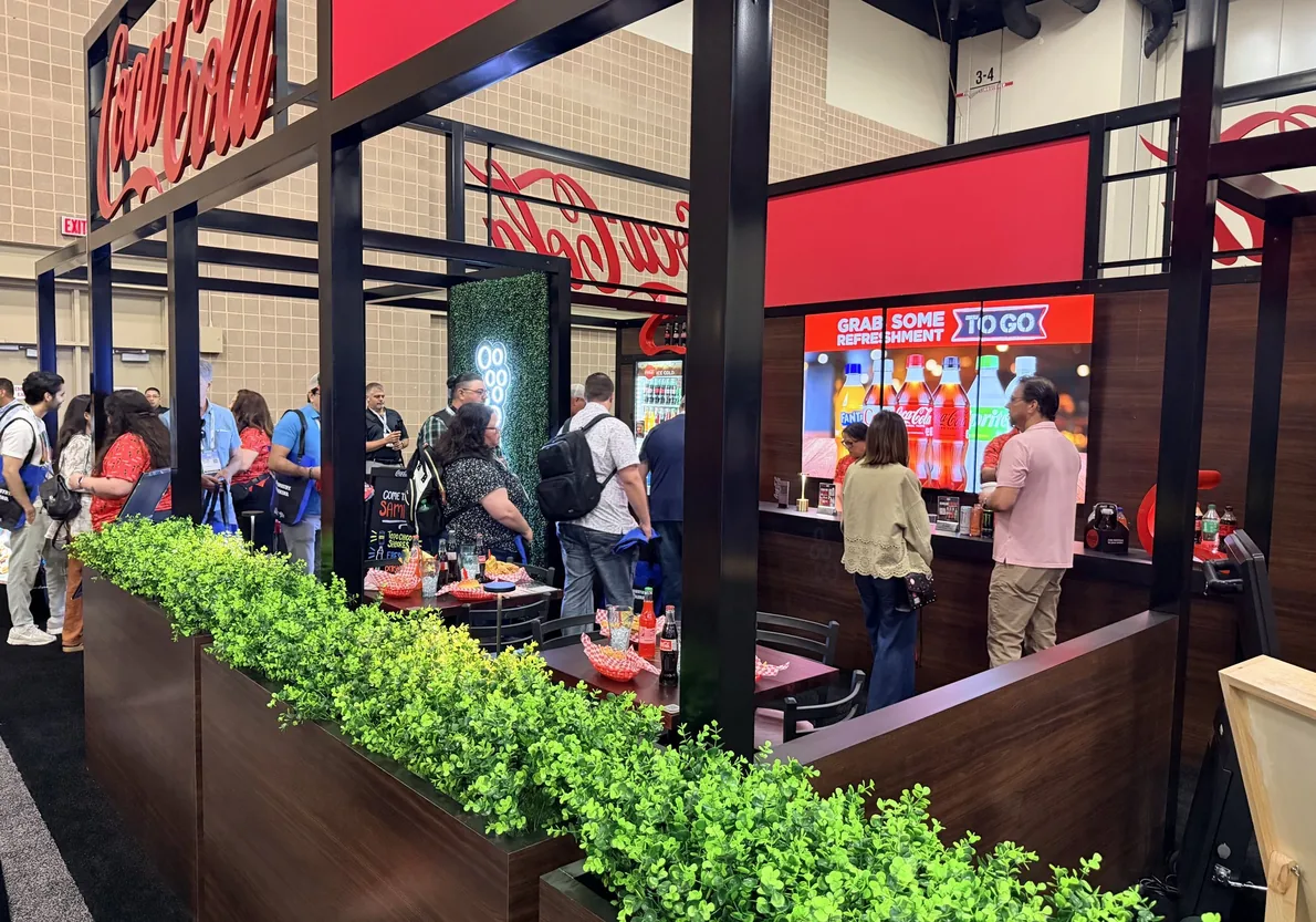 Visitors at the Coca-Cola booth, Texas Restaurant Association Show 2026, with a Grab some refreshment to go screen