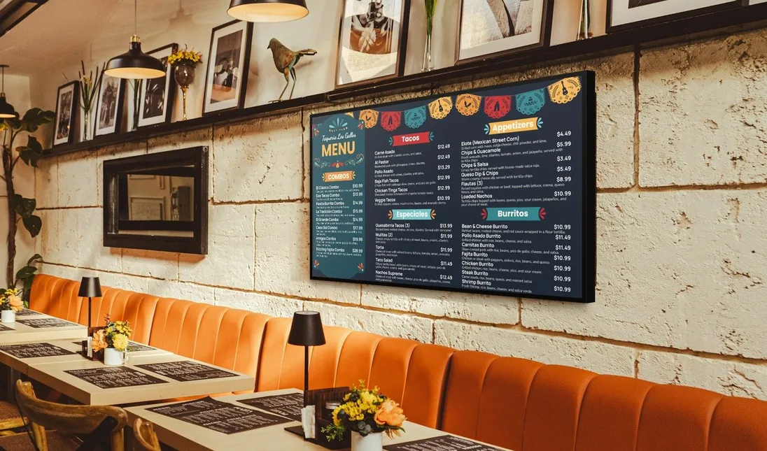 A taqueria menu as a finished menu board on a TV above an orange banquette