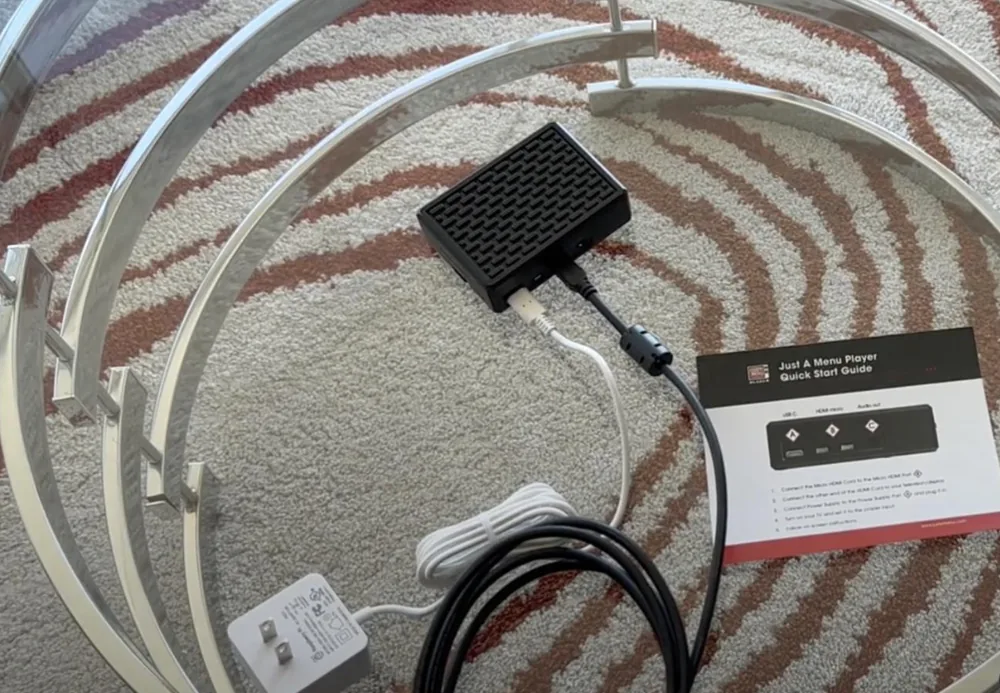 A JAM Player connected with HDMI and power, next to its quick start guide