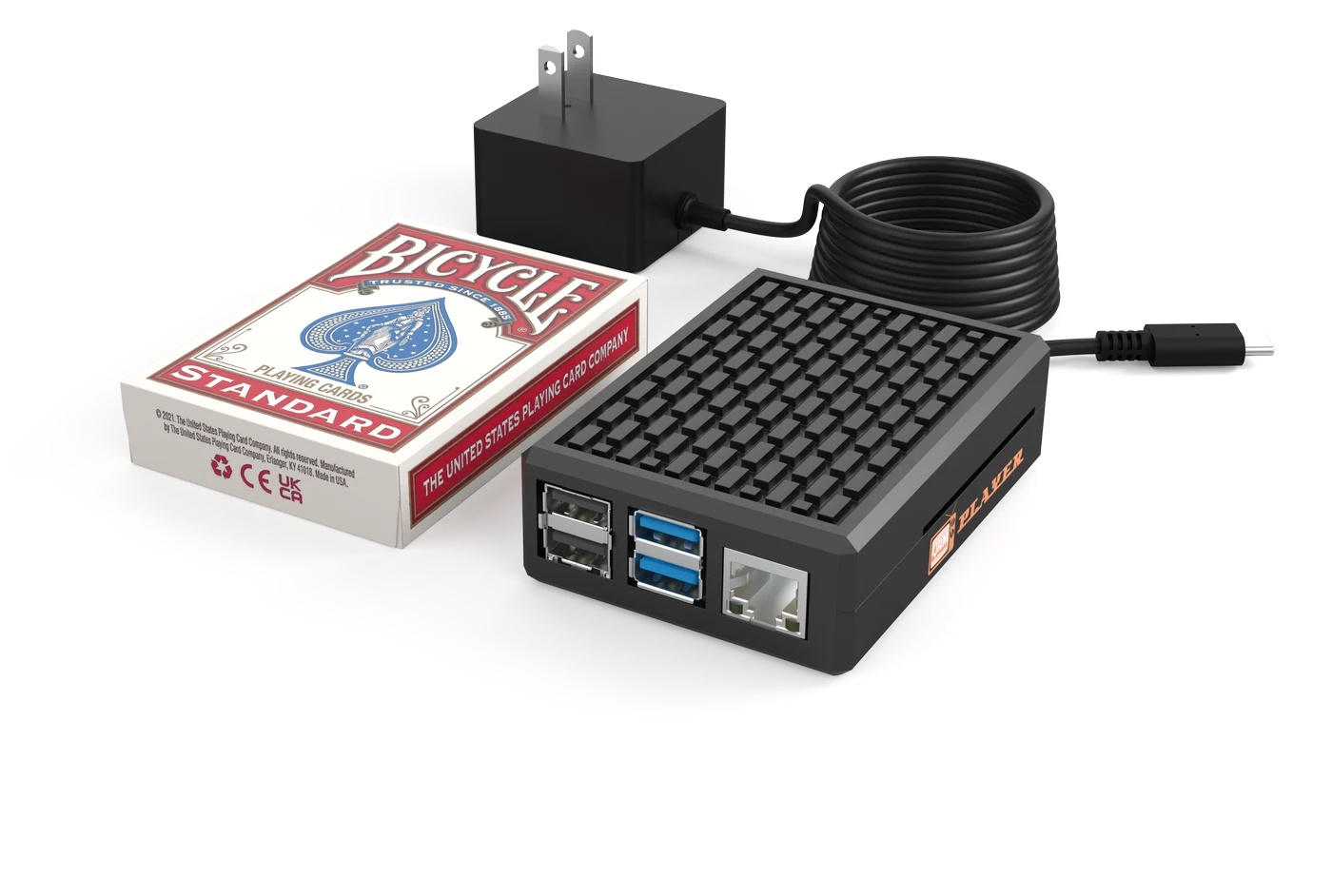 The JAM Player with its power adapter, next to a deck of playing cards for scale
