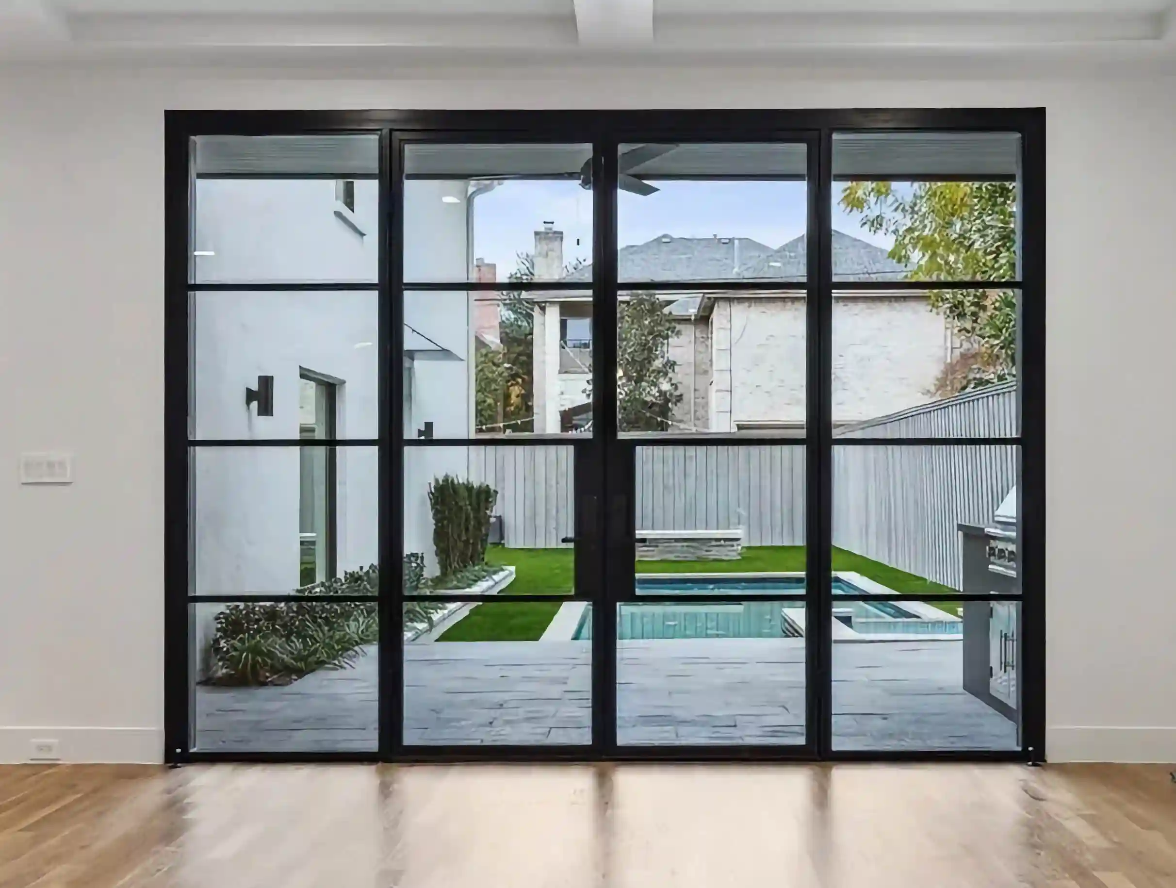 in a modern home, looking at a large glass and black iron wall looking over the back yard