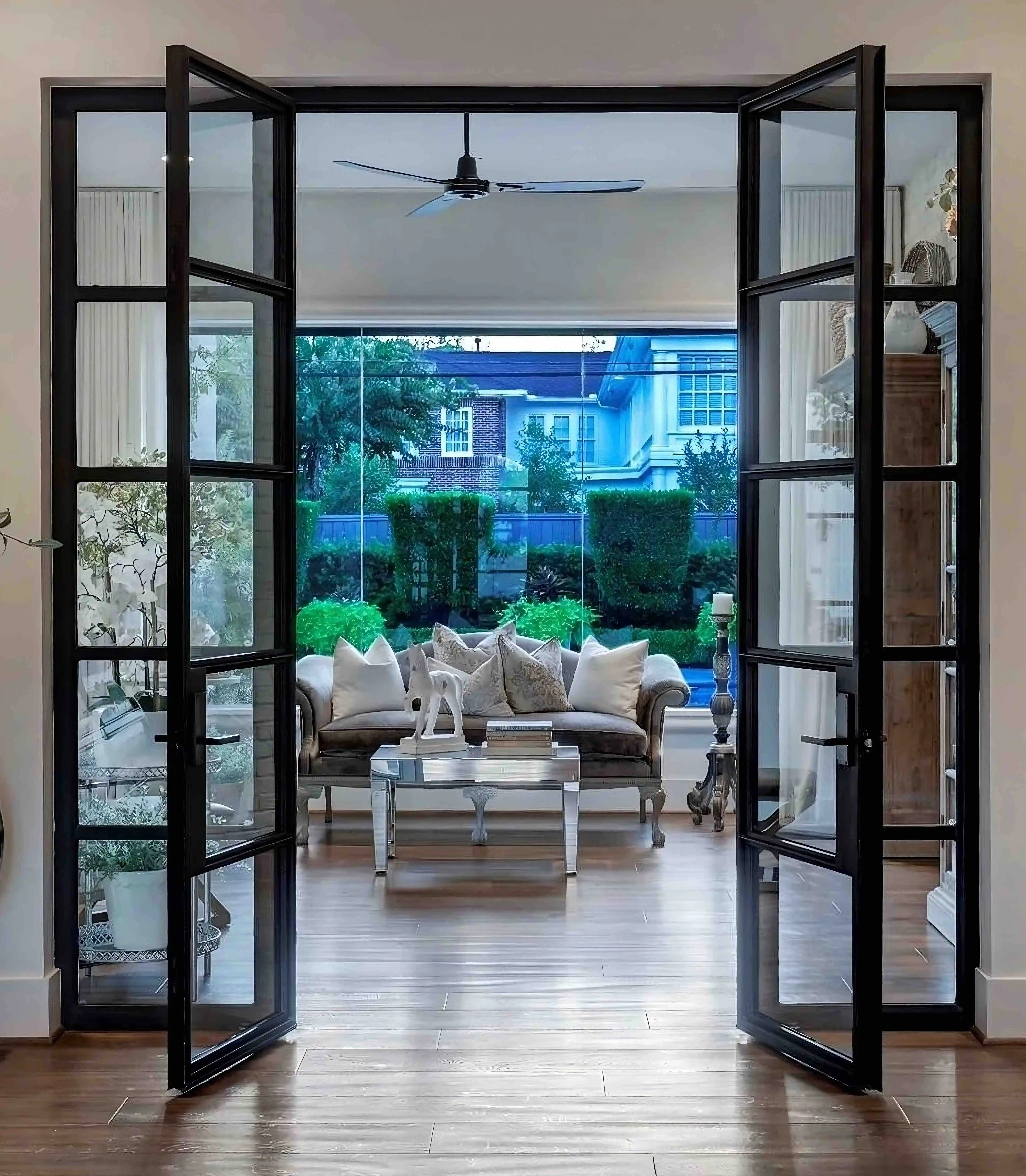 an inside view of two very large black iron and glass doors that are open and leading outside