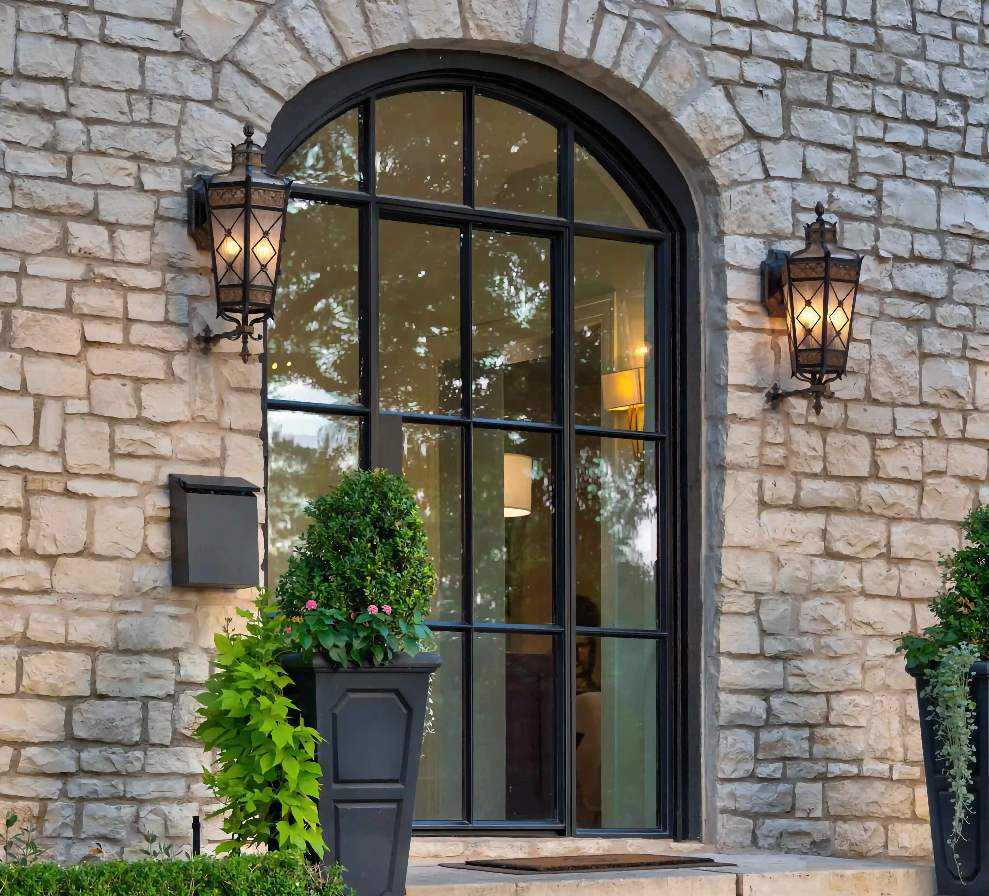 a zoomed in view of a grey stone home with a large glass and black iron front door