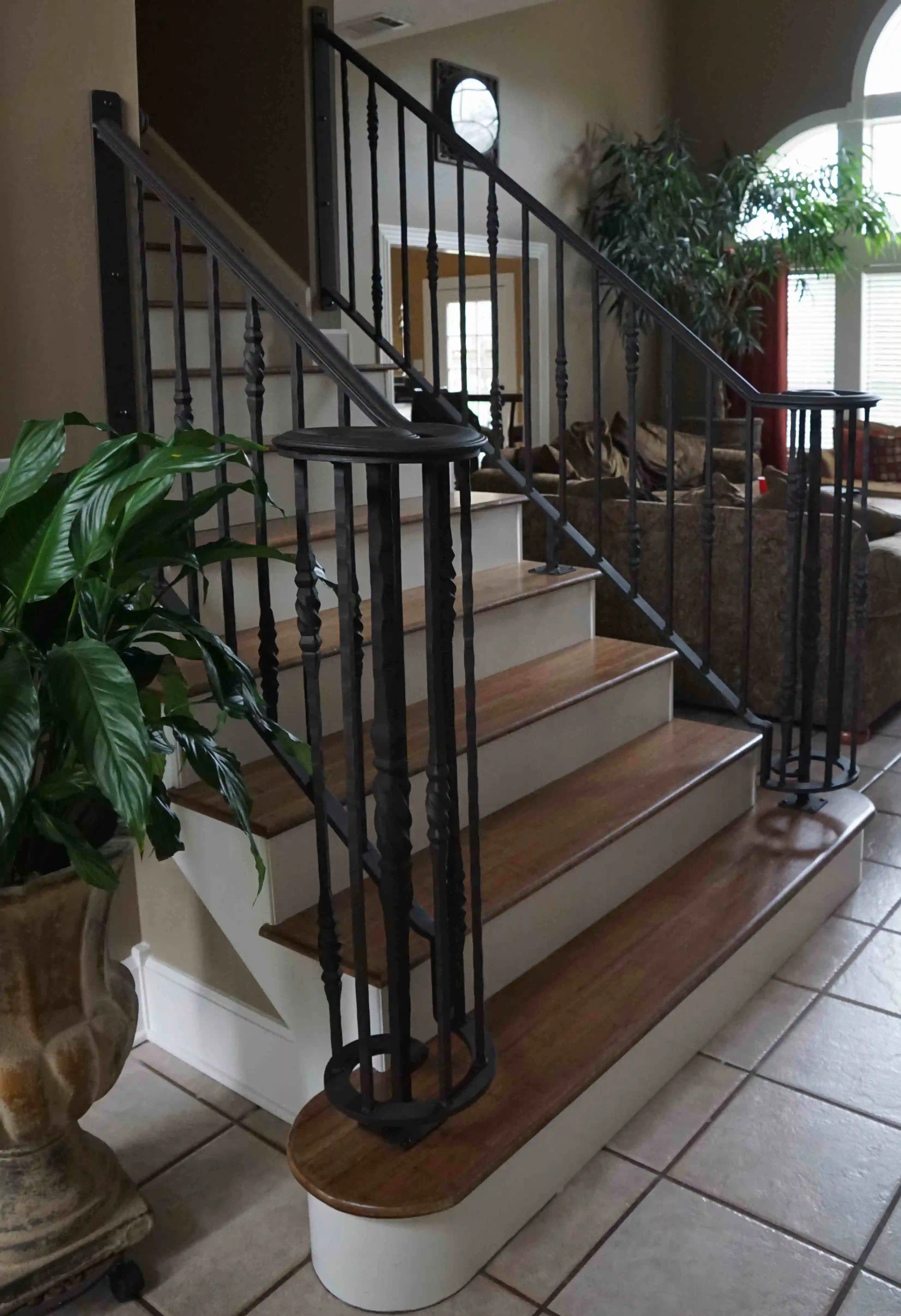 a black iron railing on both sides of wooden stairs