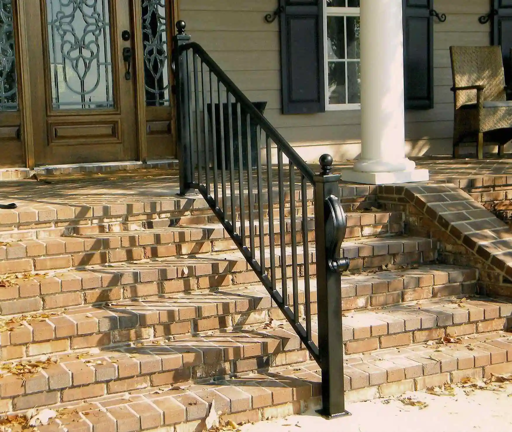 a black iron railing in the middle of red brick stairs leading to the front of a home