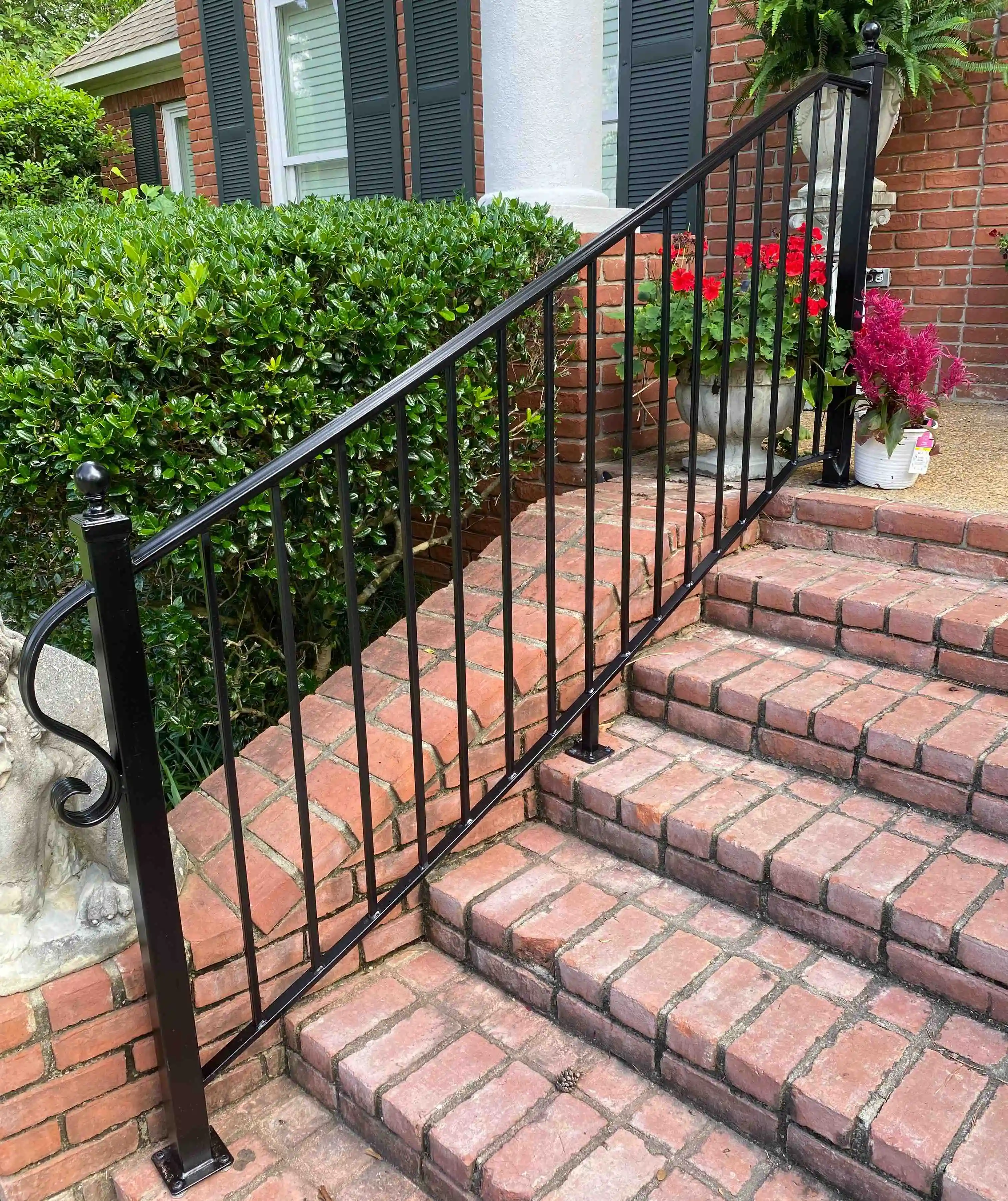 a black iron railing going up one side of brick stairs outside the front of a home