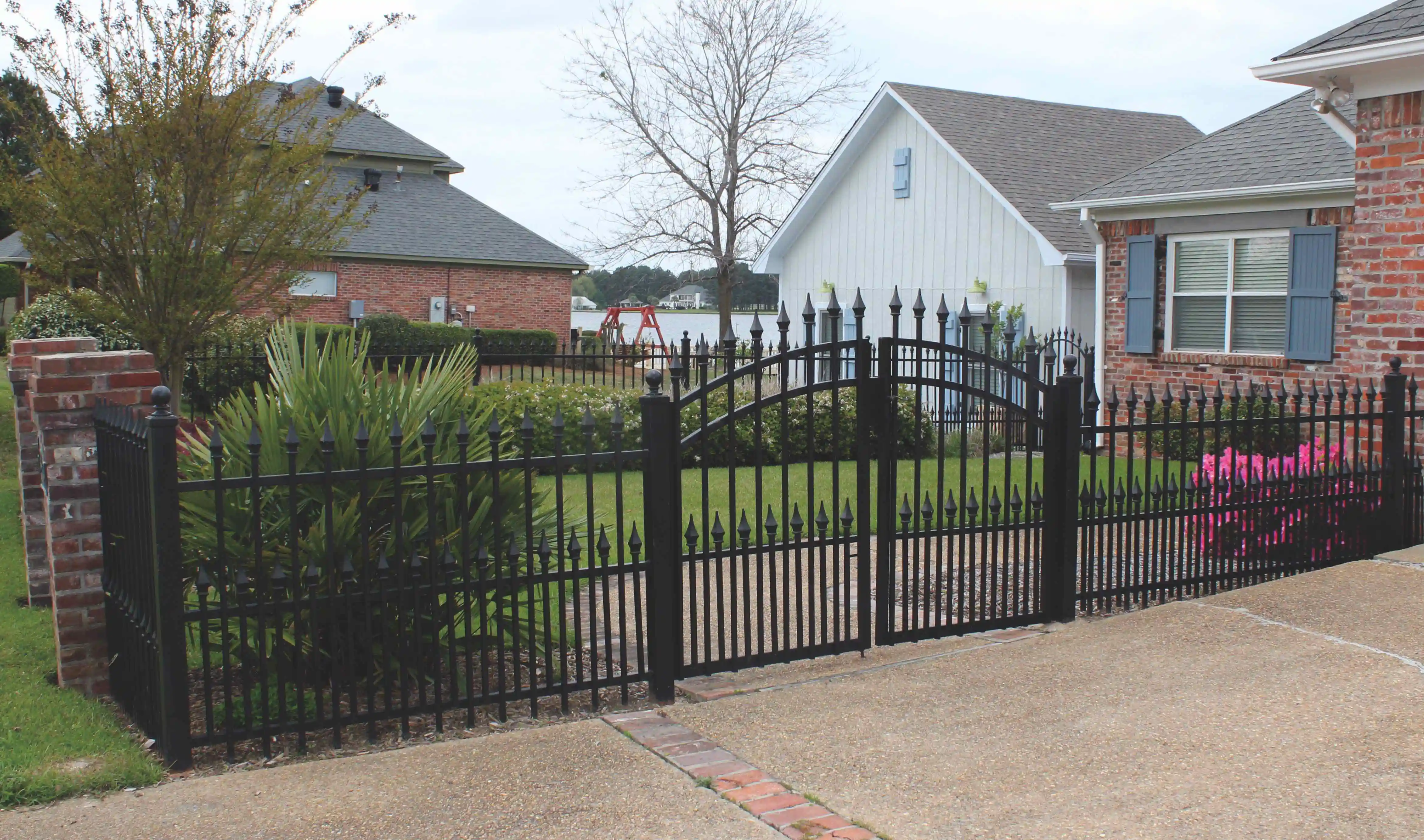 a black iron fence with pointed tops and a house behind it